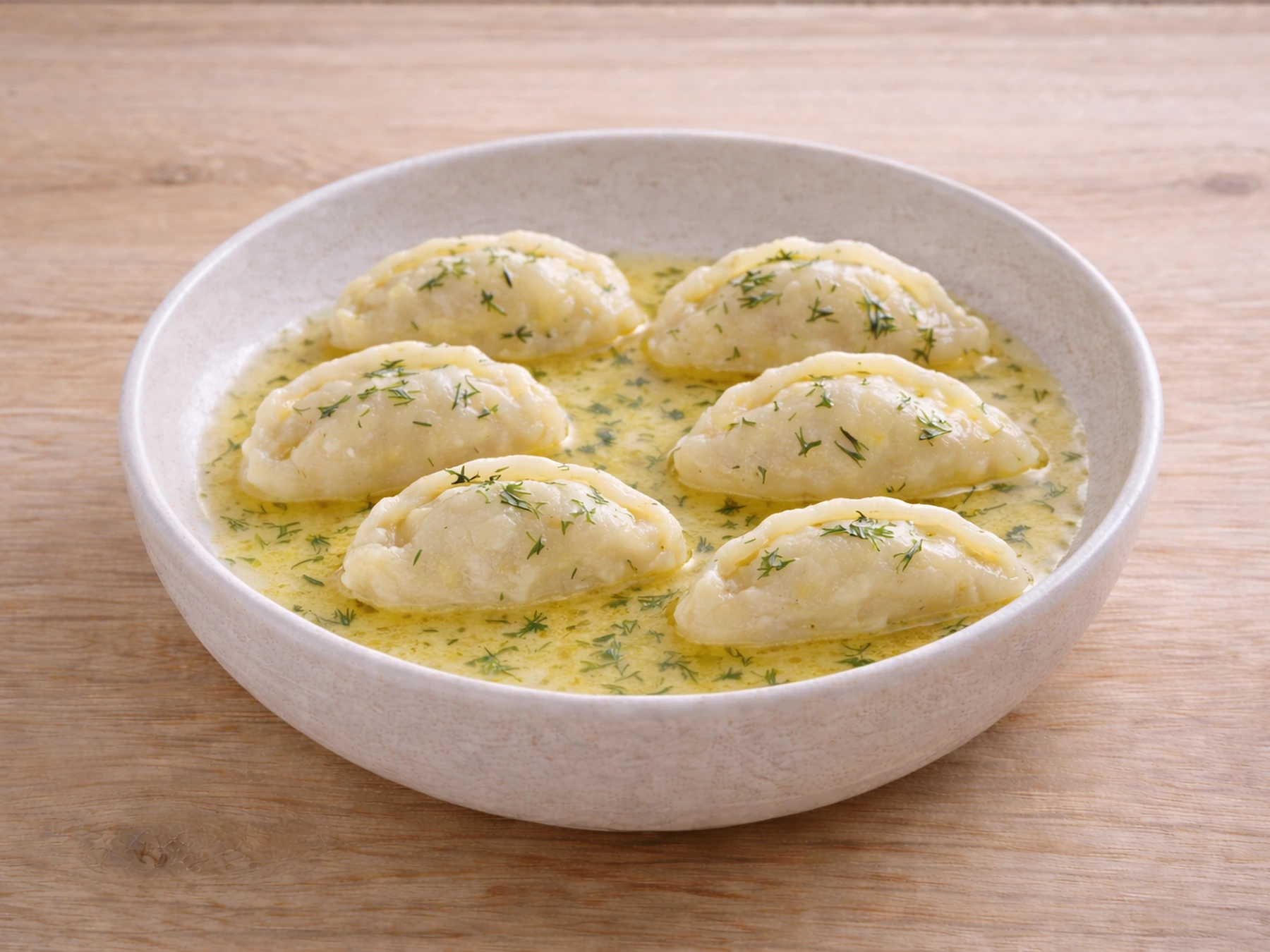 Mini pierogi ruskie z masełkiem na białym talerzu